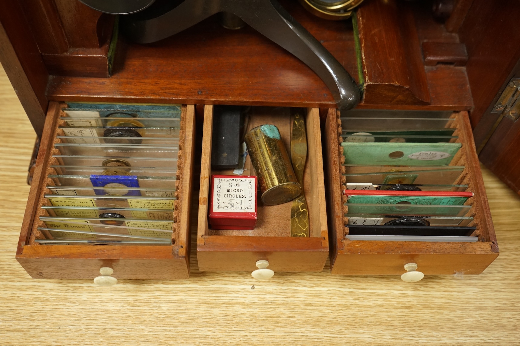 A Victorian binocular brass microscope, unsigned, in a fitted, glass fronted case with a good selection of alternative lenses and accessories, all in fitted compartments, plus three integral drawers to hold microscope sl